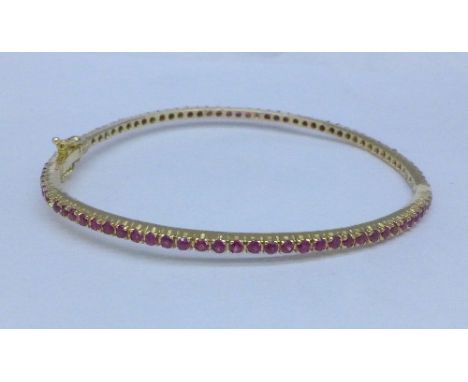 An 18ct gold bangle set with red stones, lacking one, 9.7g