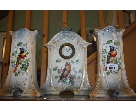 A three piece ceramic Garniture, architectural in shape, the centre piece having a brass cased Clock with clockwork mechanism