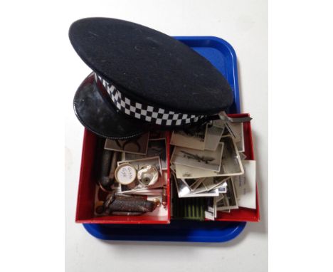 A tray containing miscellaneous to include policeman's hat, vintage pocket knives, glass eye, sew on patch, monochrome photog