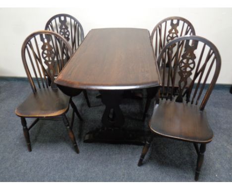 An Ercol solid elm and beech drop leaf table together with a set of four wheel back chairs in an antique finish 