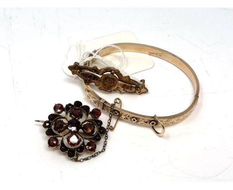 A 9ct gold bangle, 6.4g, together with two antique yellow metal brooches one is set with garnets. (3)