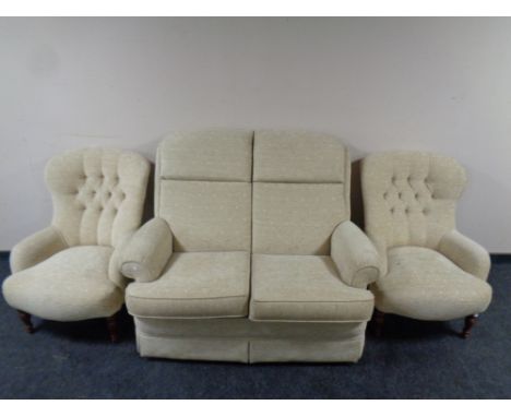 A Parker Knoll two seater settee together with pair of button back armchairs upholstered in a beige fabric 