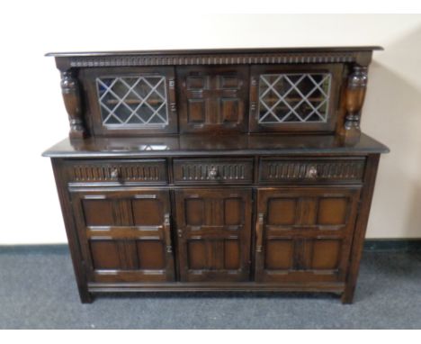 An Ercol solid elm and beech triple door buffet back sideboard in an antique finish 