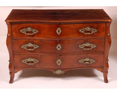 An 18th century French provincial walnut commode, having a serpentine front, three drawers each with swept cast brass mounts,