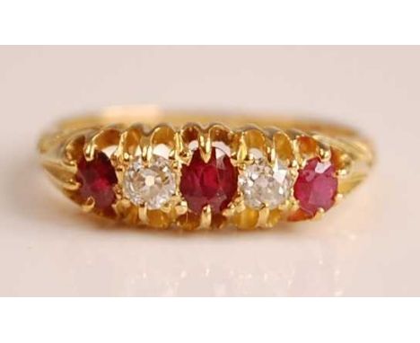An Edwardian 18ct yellow gold, ruby and diamond five stone half hoop eternity ring, featuring three graduated oval faceted ru