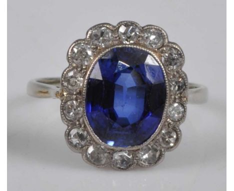 A white metal, synthetic sapphire and diamond set ring, arranged as an oval cut sapphire weighing approx 2.1 carats, within a