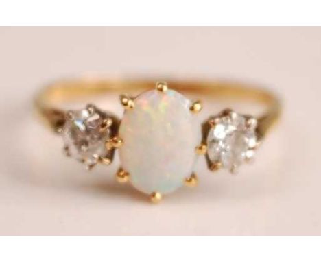 A yellow and white metal, opal and diamond three-stone ring, having a centre oval white opal cabochon, flanked on either side