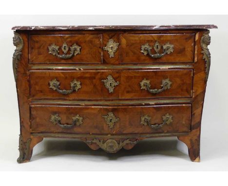 An 18th century French provincial walnut commode, of serpentine outline, having a veined rouge marble top, gilt metal mounts,