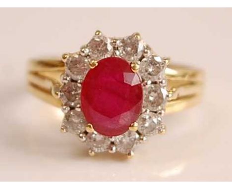 A yellow and white metal, ruby and diamond oval cluster ring, featuring a centre oval faceted ruby within a border of ten rou
