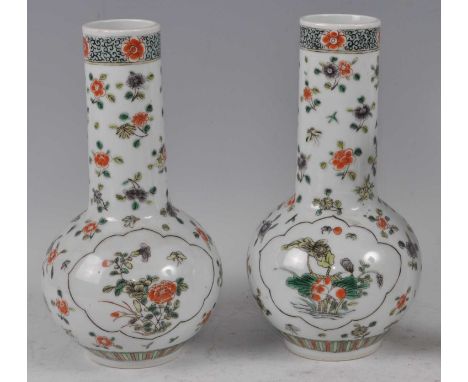 A pair of 19th century Chinese famille rose bottle vases, each enamel decorated with opposing floral reserves within borders 