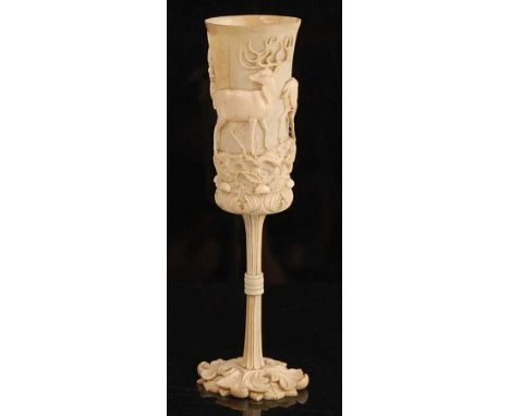 A late 19th century North European carved ivory hunting goblet, probably German, the cup carved in high relief with a continu