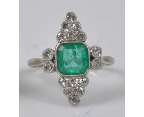 A white metal Art Deco emerald and diamond cluster ring, featuring a centre octagonal cut emerald with a triangular cluster o