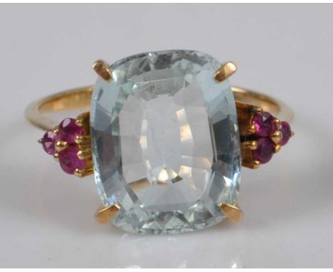 A yellow metal, aquamarine and ruby dress ring, comprising a cushion shaped aquamarine in a four-claw setting, with a trefoil