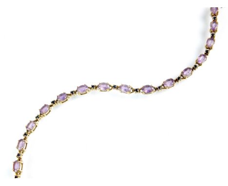 A 9ct gold amethyst and sapphire bracelet, designed as sixteen oval mixed cut amethysts, interspersed with faceted blue sapph