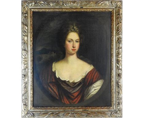Manner of Godfrey Kneller (1646-1723) Portrait of a lady, half length in a painted oval, wearing a red cloak, with a distant 