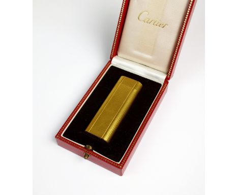 A cased Cartier lighter, the engine turned gilt lighter of elongated rectangular form presented within original box, engraved