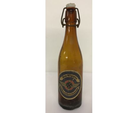 A WW2 style brown glass German beer bottle with metal and ceramic bottle top and paper label.  Approx. 28cm tall.