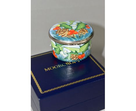 A BOXED MOORCROFT ENAMELS TRINKET BOX, of cylindrical form, decorated with sprigs of fir, fir cones, mistletoe and holly on a