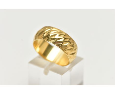 A WIDE YELLOW METAL TEXTURED BAND, approximate band width 7.6mm, stamped 18ct, ring size centre N, approximate gross weight 7