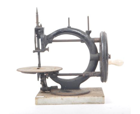 A vintage 19th century cast iron sewing machine, with a marble base. Featuring a ceramic hand crank, with rotating cogs, need