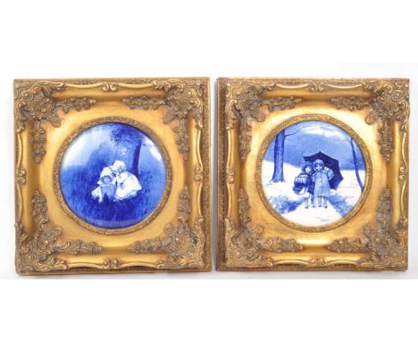 Two vintage 20th-century framed Doulton-style blue / white porcelain plaques, both depicting two children in nature. Housed w