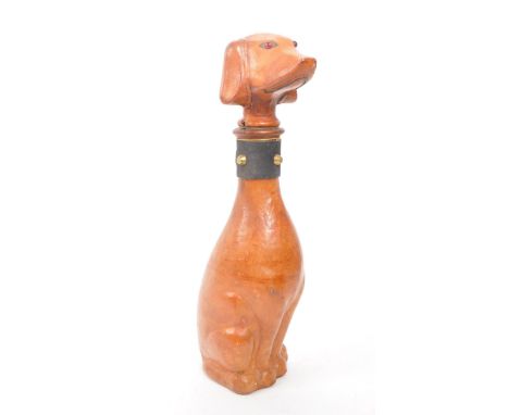 A leather covered glass decanter with a rubber stopper, designed to look like a dog. Additional features include red glass ey