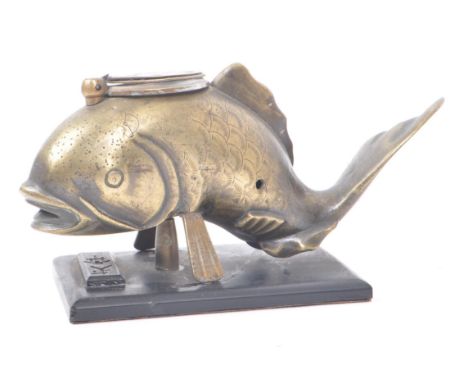 An early 20th century Japanese brass inkwell, in the shape of a fish mounted on a wooden base. Inkwell lid opening to the top