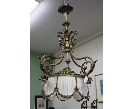 AN ANTIQUE GILT METAL HANGING LIGHT FITTING with four scrolling supports and pleated shade, 98cm high