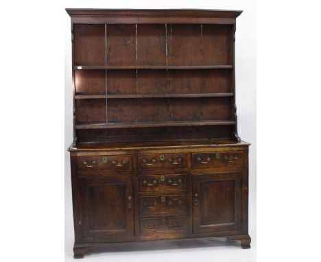 AN 18TH CENTURY OAK WELSH DRESSER fitted with fielded panel door and standing on shaped bracket feet, 155cm wide x 210cm high