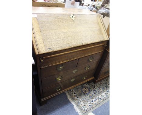 A GEORGE III OAK BUREAU the fall front opening to reveal pigeon holes and drawers above two short and two long drawers standi