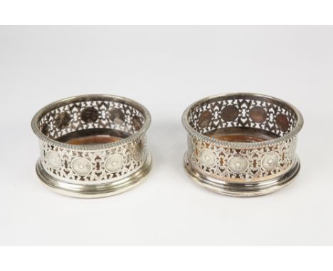 PAIR OF ELECTROPLATED WINE BOTTLE COASTERS, each of typical form with fancy scroll pierced decoration and circular engine tur