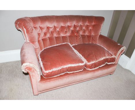 An early 20th century button back salmon pink covered two seat sofa, 75cm H, 140cm W, 60cm D 