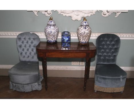 A pair of early 20th century style, blue velvet button back boudoir chairs. Bow fronts, tassels and upholstered seats.