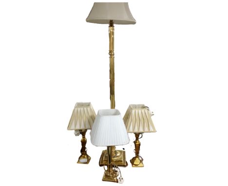 A brass standard lamp together with three brass table lamps, all with shades.