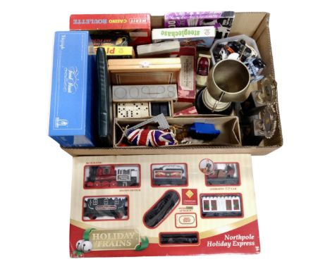 A box containing board games, dominoes, plastic animals, trophies, die cast cars, a Holiday Express train set.