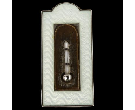 An Art Deco miniature novelty enamel thermometer, unmarked silver frame with engine turned guilloche decoration and strut bac