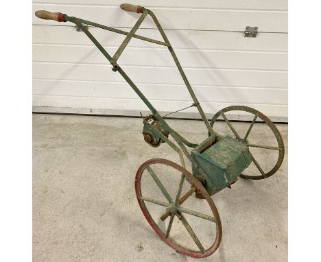 A vintage push seed drill with cast iron wheels and wooden handles. Painted red and green.  Approx. 120cm tall.