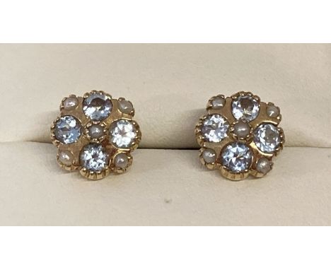 A pair of 9ct gold blue topaz and seed pearl stud earrings by Luke Stockley, London. Each earring set with 4 round cut blue t