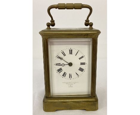 An antique Goldsmiths Company brass carriage clock with French movement and glass panel sides. White enamel face with Arabic 