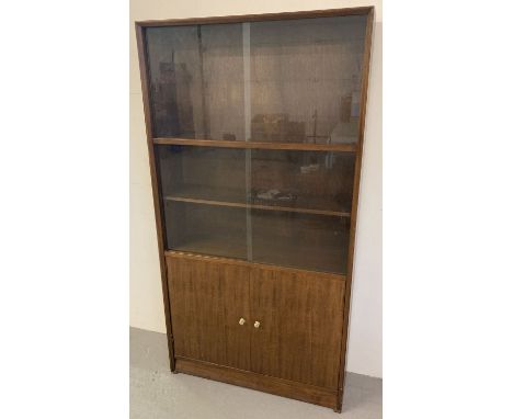 A vintage 1960's dark teak glass fronted bookcase by Herbert E Gibbs. With glass sliding doors, 2 door cupboard and adjustabl