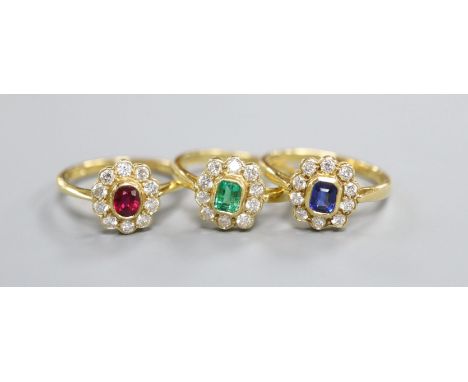 Three modern 18ct gold and gem set cluster rings, to include, emerald, ruby and sapphire, sizes L &amp; L/M.