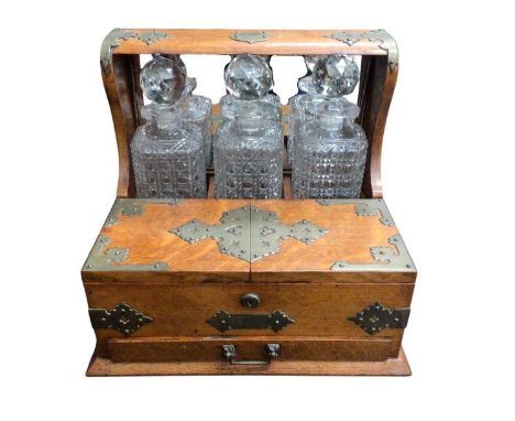 Edwardian oak cased three-bottle tantalus with brass mounts and handles and Bramah lock, 36cm wide