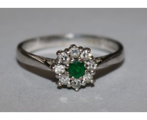 A 18ct white gold emerald and diamond cluster ring, size L