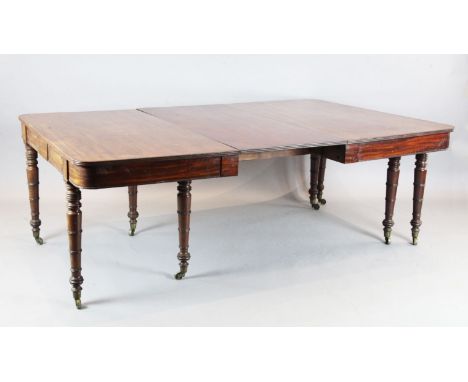 A large Regency mahogany extending dining table, with D shaped ends and three leaves, on ring turned tapered legs, fitted bra