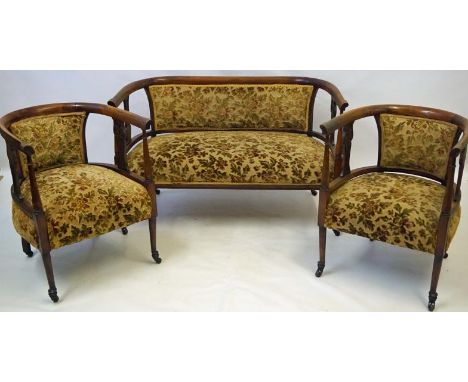 An Edwardian walnut show wood framed three piece salon suite, comprising two seater settee and two armchairs, each with folia