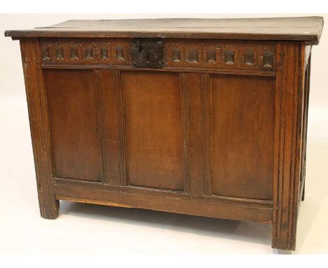 A late 17th/ early 18th Century oak coffer, the hinged lid above chisel carved frieze and three panels, raised on stile feet,