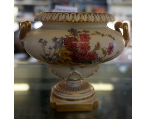 A Royal Worcester blush ivory twin handled urn, with hand painted floral decoration, raised upon stepped base (af)