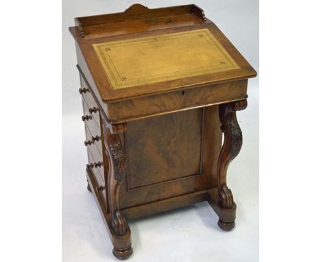 A Victorian carved walnut Davenport, the gilt tooled leather inset sloping writing surface hinged to enclose a satin maple wo