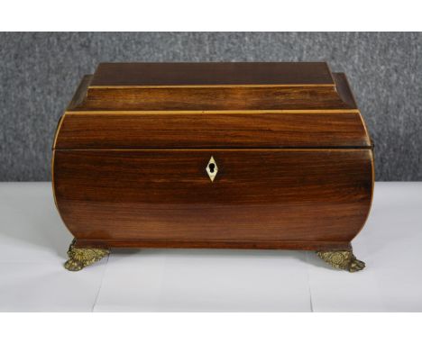 A Regency mahogany and satinwood strung tea caddy with lidded compartments and a mixing bowl raised on brass lion's paw feet.