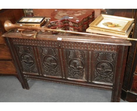 An oak coffer with four panel front, carved with heads amongst foliage